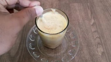 Bir bardak Teh Talua karıştırılıyor, Batı Sumatra, Endonezya 'dan geleneksel bir Minangkabau yumurta çayı. Yumurta sarısı, çay ve şekerden yapılan popüler bir kahvaltı içeceği..