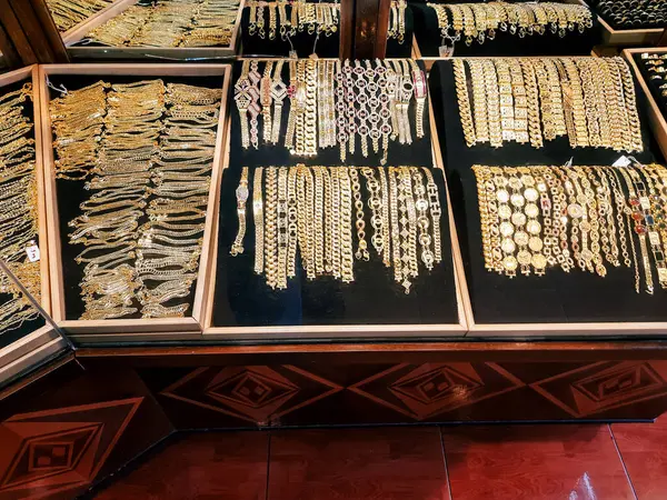 Bir mağazada sergilenen altın bilezik ve mücevher çeşitleri. Siyah kadife bir yüzeye düzgün dizilmiş çeşitli tasarımlar ve desenler.