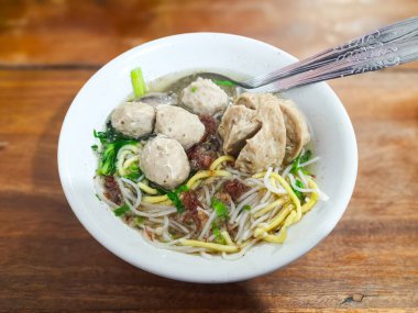 Geleneksel Endonezya sokak yemekleri olan bakso urat, sarı erişte, pirinç vermicelli ve ahşap bir masada et suyu ile servis edilir.
