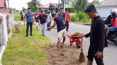 Pariaman, Endonezya - 28 Mayıs 2025: Geleneksel araçlarla Naras Hilir 'deki bir toplum temizliği sırasında köy temizlik işçileri yol kenarındaki aşırı büyümeyi temizledi
