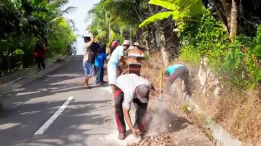 Pariaman, Endonezya - 25 Haziran 2025: Sungai Rambai 'deki bir toplum temizliği sırasında köy temizlik işçileri yol kenarındaki aşırı büyümeyi temizledi