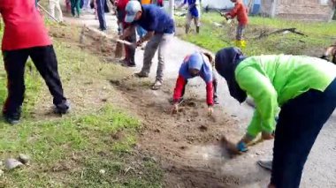 Pariaman, Endonezya - 23 Haziran 2025: Manggung 'daki köy temizliği sırasında yol kenarındaki çimleri geleneksel aletlerle temizleyen köy görevlileri.