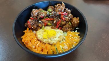 Lezzetli karabiberli tavuk kasesi kızarmış yumurta, taze sebze ve havuç dilimleri ile servis edilir, mayonez ile süslenir, susam tohumları ve acı dilimlerle süslenir.