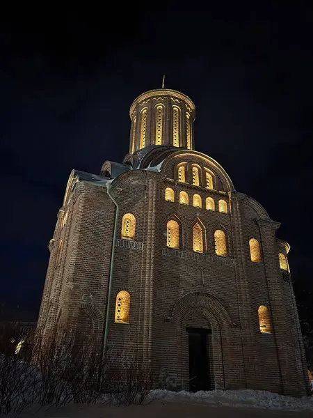 Bir parkta, kardan temizlenmiş bir yol, bir kış gecesi, yanlarındaki aydınlatma ve banklarla. Yol aydınlık bir kiliseye çıkıyor.