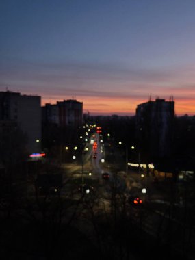 Alacakaranlıkta sokak ışıkları ve karanlık gökyüzünde dramatik bulutlar.