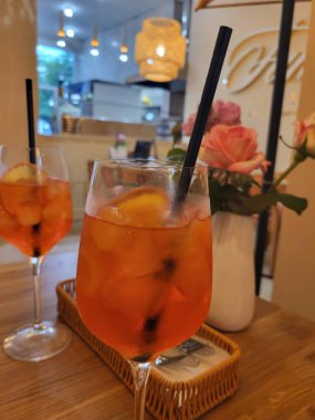 Pembe güllerin yanında buz ve portakal dilimli Aperol, mükemmel bir besin ve içecek kompozisyonu..