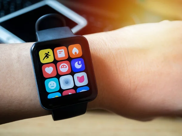 stock image Close up of the arm of Asian girl wearing a digital wrist watch and a blurred image of a mobile phone put on a notebook behide.