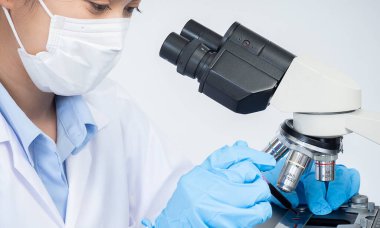 Biochemical research scientist working with microscope for vaccine development in pharmaceutical research labolatory, selective focus