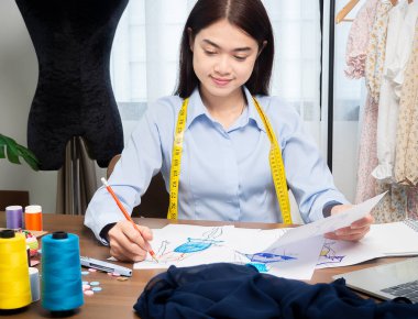 Asyalı giyim tasarımcıları tekstil kumaş kostümleri çiziyor. Yeni bir kıyafet koleksiyonu oluşturuluyor, tasarımcının çalışmalarının oluşturulması.