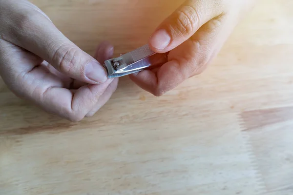 Close-up of woman clipping her nails with nail clippers, after cutting short nails, dark, rough skin, and concept to keep clean nail care.
