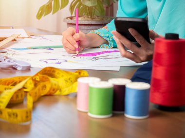 Müslüman kadın moda tasarımcısının çalıştığı, akıllı telefon ve tablet kullandığı küçük bir işletme.