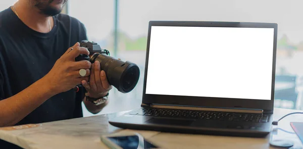 漂亮的年轻摄影师在咖啡店里用相机和带有空白屏幕的笔记本电脑一起工作 — 图库照片