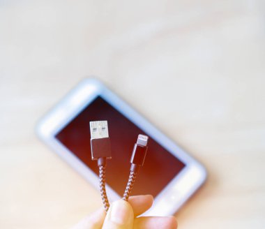 Kadın ellerinin evdeki akıllı bir telefona USB şarj kablosu takmasına yakın. USB kablo yükleme kavramı.