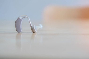 Sağırlık ve işitme kaybı tedavisi için işitme cihazını kapatın. Hafif ahşap masada işitme cihazı ve seçici odak.