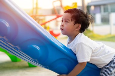 Çocuk parkındaki çocuklar. Asyalı çocuklar okul bahçesinde kaydırak oynuyorlar. Sağlıklı aktivite. Yaz tatili eğlencesi.