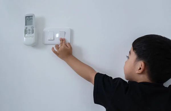 stock image Back view at little careless child boy exploring house playing turning light switches, home electricity danger security, electric shock risk and kids safety, energy power saving concept, copy space