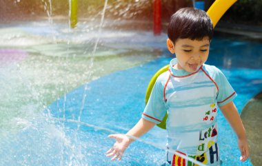 Küçük tatlı çocuk çeşmedeki su parkında suyla oynarken eğleniyor. Şehir konseptinde yaz.