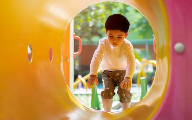 Siyah saçlı çekici bir çocuk tüp koridorda sürünüyor. Çocuk parkı. Tünel konseptiyle oynayan çocuklar.