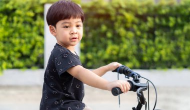 Önce çocuk bisikleti. Kid 'in şehir parkındaki bahçe bahçesindeki spor aktivitelerinin kırpılmış görüntüsü..