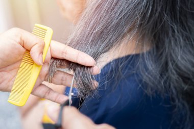 Yaşlılar için saç kesimi. Büyükanneni evde kesme işlemi. Kuaför kıdemli kadının saçlarını kesiyor..