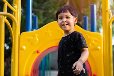 Asyalı küçük çocuk yazın gündüz vakti oyun sahasında oynarken eğleniyor. Açık hava aktivitesi. Rol yapma konsepti. Dış eğitim