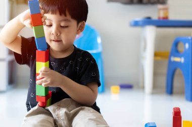 Küçük Asyalı şirin çocuk evde yaratıcı oyuncak blokları oynuyor. Yaratıcı anaokulu çocukları bir blok kulesi inşa ediyorlar. Bebek ya da bebek için eğitici oyuncaklar.