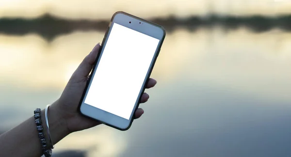 stock image Close up view young woman sitting near the river  in the natural park and using smart phone. Isolate screen.