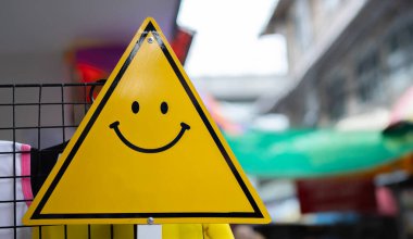 Bulanık pazar yolu geçmişine sahip gülen yüzlü üçgen yol tabelasının kırpılmış görüntüsü. Pozitif düşünce, zihinsel sağlık değerlendirmesi, dünya sağlık günü konsepti