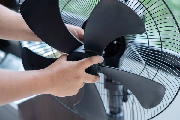 Erkek ellerinin yatay fotoğrafını kapat ve evdeki kirli elektrikli vantilatör bıçağını temizledikten sonra parçaları yerine koy. Cihaz bakımı. Ev işi ve ev işi kavramı.