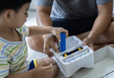 Mutlu bir oğlun yeni bir tane alması ve evde babasının oyuncak treniyle oynaması üzerine seçici bir odaklanma. Çocuklar için yaratıcı oyunlar.