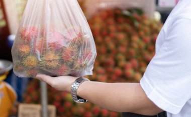 Rambutan çantasını kapat. Marketten Rambutan alan kimliği belirsiz bir adam. Organik ürün ve meyve konsepti.