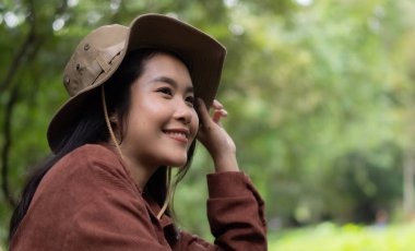 Çekici kız gezgin, tatil gezisi sırasında doğa ormanında mutluluk ve eğlenceyle otururken etrafına bakar ve keşfederdi..