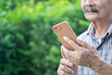 Doğada cep telefonuyla mesajlaşan gülümseyen son sınıf öğrencisinin görüntüsü. Seçici odak.