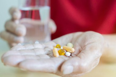 Yaşlı adamın el ele tutuşup su bardağıyla hap içtiği seçmeli bir odak noktası. Sağlık, tedavi, yaşlanma konsepti