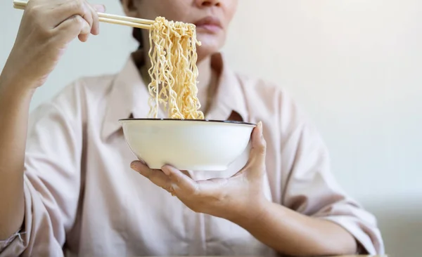 End of month. Alone depressed Asian woman,  woman using chopsticks eating instant ramen, noodles, cheap food and no money for dinner