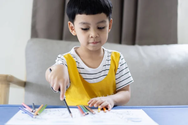 幸せなアジアの少年が描いた絵と 自宅で机の上に座っている間にカラフルな鉛筆を使用した肖像画 ホビー タレント クリエイティビティコンセプト — ストック写真