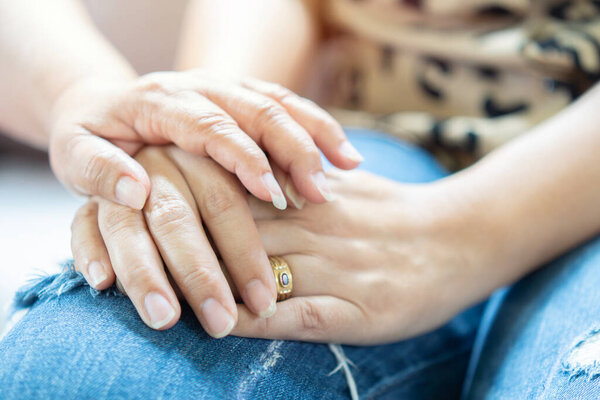 Close up of middle-aged 60 woman holding hand her daughter feel stressed depressed melancholic for loss. Senior mother show empathy and love.