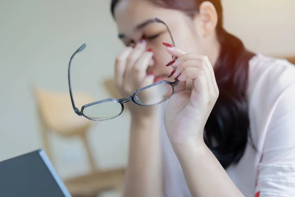 Tired student or worker rubbing irritable eyes feeling fatigue from computer work concept, overworked woman taking off glasses to relieve eye strain suffering from bad eyesight vision problem concept. Selective focus on subject.