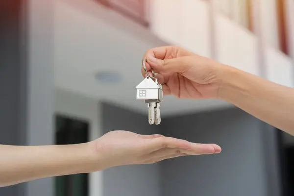 Selective focus of hand of real estate agent giving house key to new home buyer. Mortgage concept. Real estate, moving home or renting property.
