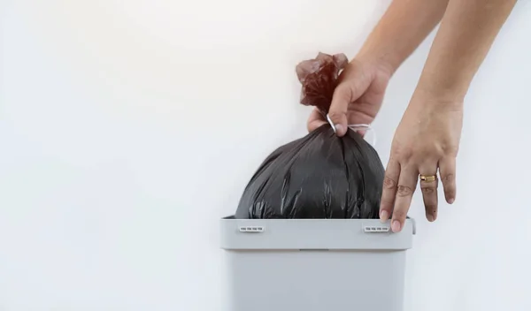 Shot of woman taking black garbage bag out of bin at home, closeup, copy space. Housekeeping concept.