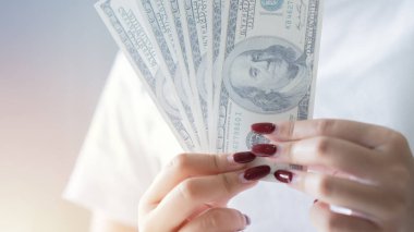Ellerinde dolar olan bir kadının kesilmiş görüntüsü. Elinde kağıt para olan bir kadının yakın çekimi. Maliye, para birimi ve insan kavramı