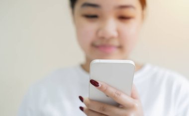 Gülümseyen esmer Asyalı kız modern teknolojilere bağımlı sosyal ağlarda mutlu mesajlar kullanıyor..