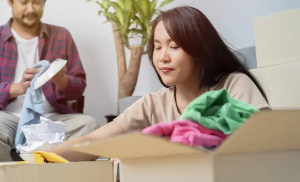 Asian couple moving into a new home and help each other to unpack the box. Beginning of a married life.