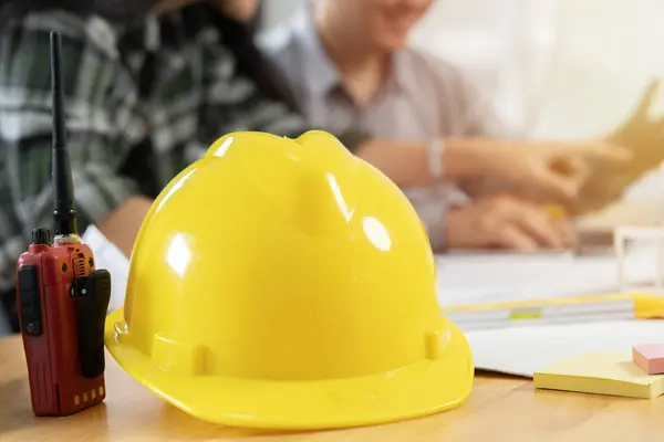 Engineer working in office with blueprints, inspection in workplace for architectural plan. Construction project, selective focus on hat