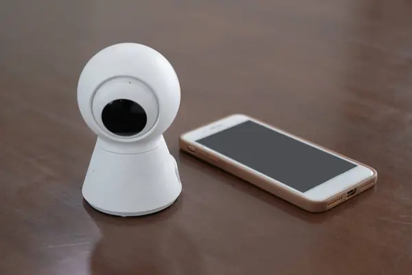 IP Camera. CCTV wireless IP security camera with 360 degrees rotating head with a smartphone on the table, Concept of home security system