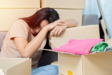 Genç Asyalı kadın eşyalarını toplayıp yeni evine taşınıyor. Yorgun görünüyor ve kutuların arasında kestiriyor. Seçici odak.