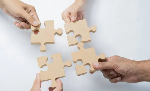 The man and woman holds in hand a jigsaw puzzle. Business solutions, success and strategy concept. Close up, top view.