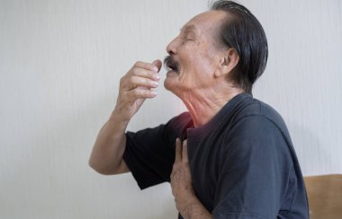 Siyah tişörtlü, öksüren, olgun İspanyol bir adamın portresi. Öksürük sorunu.