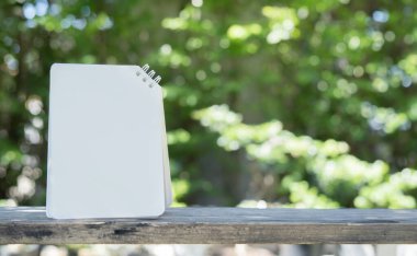 Kağıt kart, doğanın arka planındaki ahşap masaya kurulmuş. Seçici odaklanma, kopyalama sapı. Tebrik kartı şablonu.