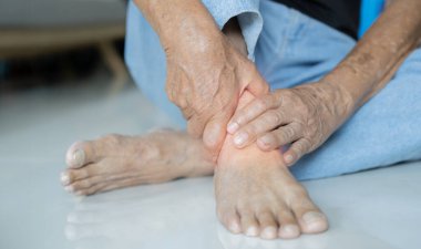 Ayağı ağrıdığı için acı çeken son sınıf öğrencisi evde yerde oturuyor. Ayak ağrısı, duyusal nöropati sorunları konsepti..